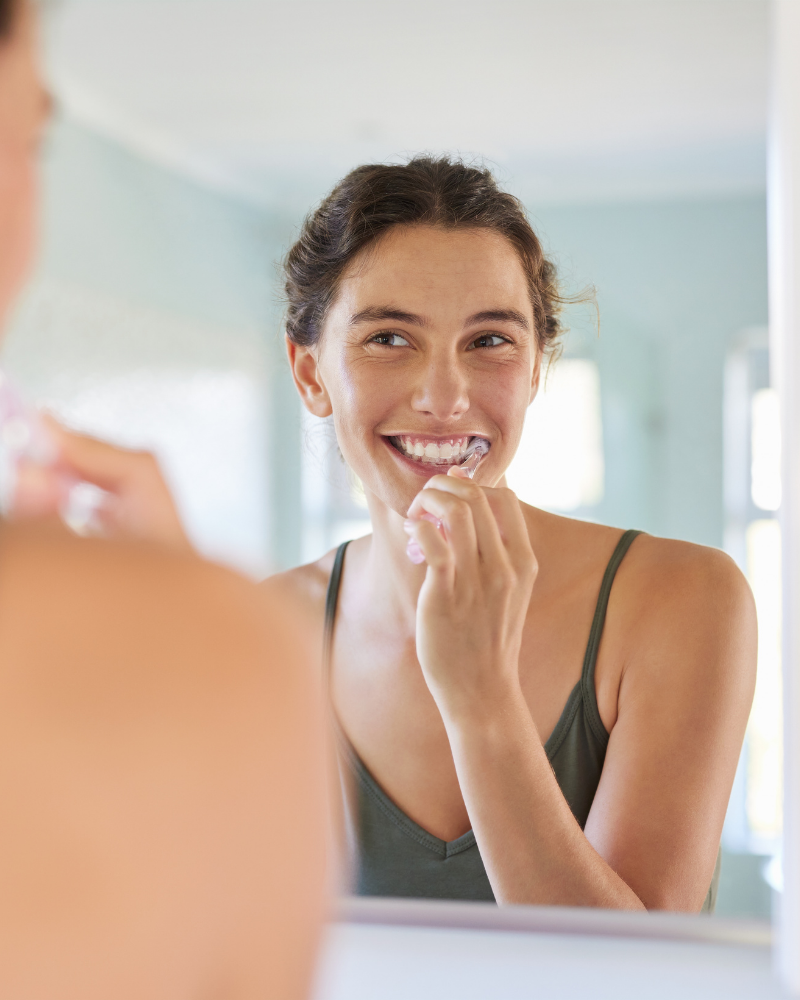A woman choosing Smiles Club clear aligners over Alignerco and smiling.